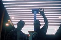 two men standing in front of a neon sign